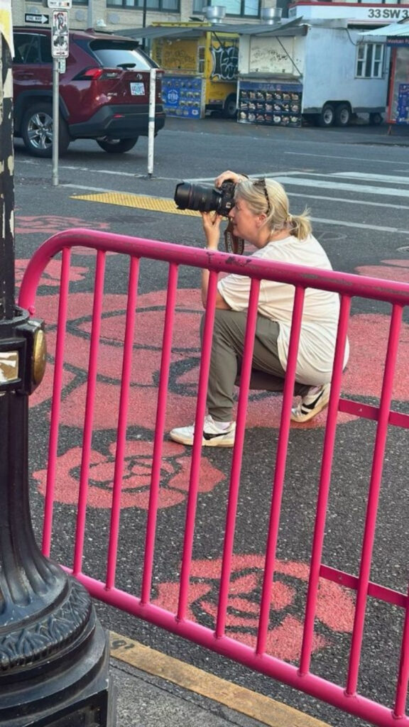 Photographer crouching with camera in hand, capturing street scenes while planning a travel calendar session.