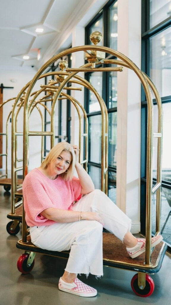Woman sitting on a hotel luggage cart, styled for planning your travel calendar as a photographer.