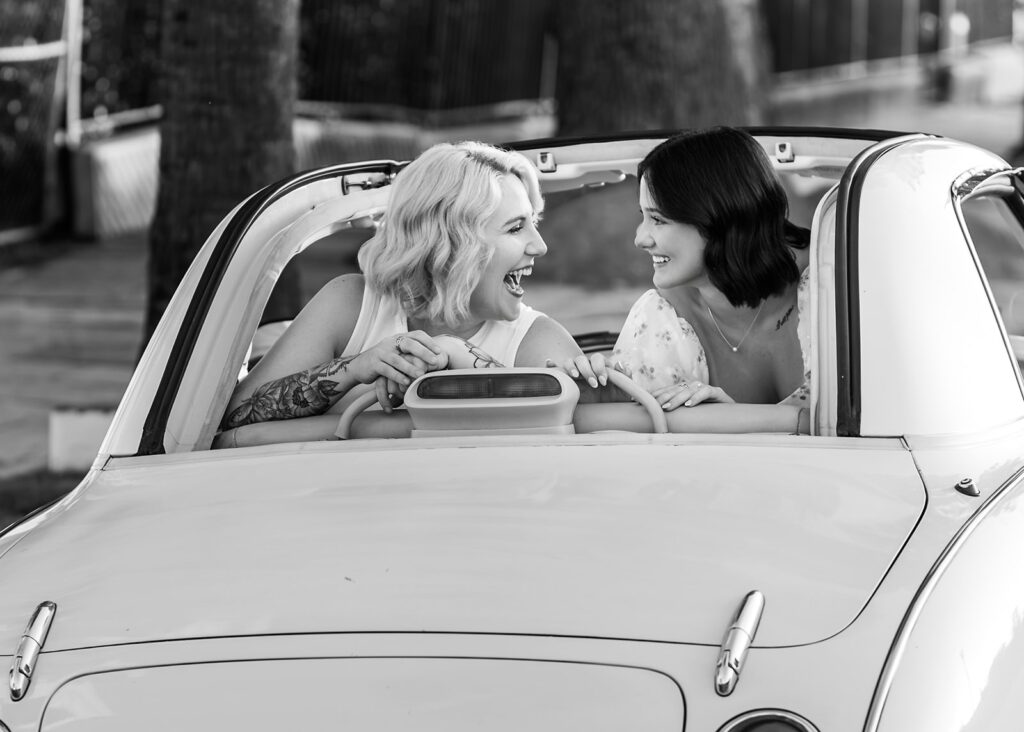 Two women laughing in a convertible during a travel session, capturing joy and connection through travel session pricing work.