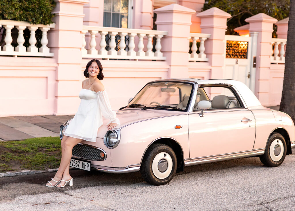 A young woman leans against The Pink Figgy during senior pictures in Charleston SC