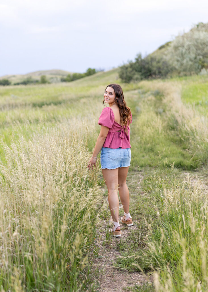 Senior portrait in tall grass wearing mauve top