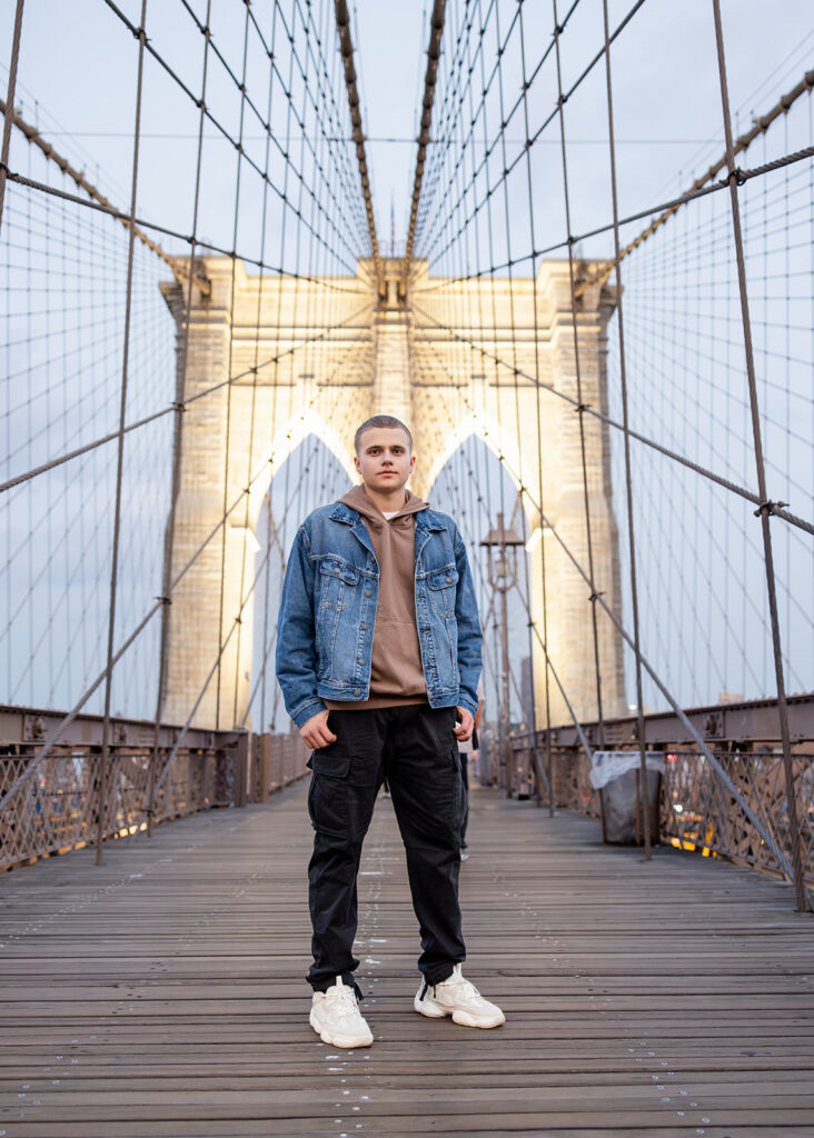 A high school student poses for a photo on a bridge during a NYC senior trip