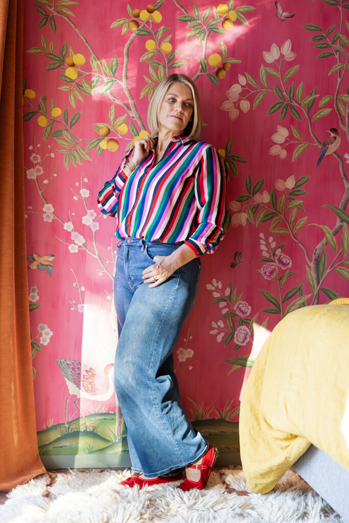 A photographer poses against vintage inspired wallpaper in an image taken during a Palm Springs photo session