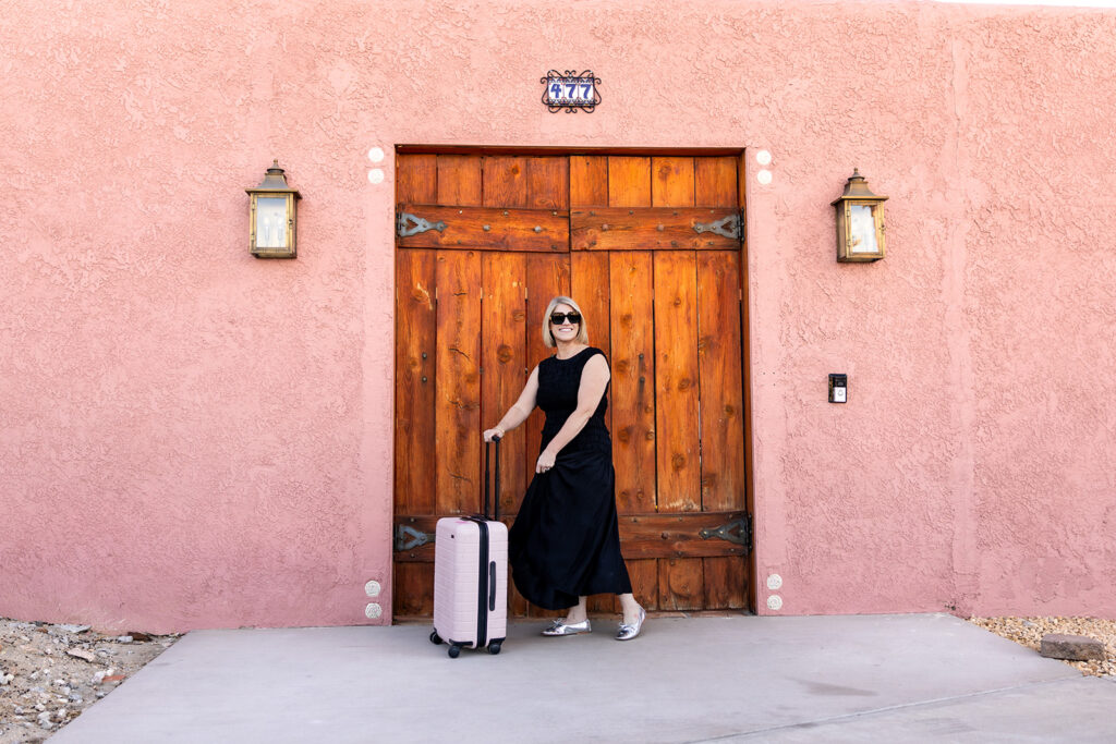 A woman in a black dress poses with her luggage in a photo for a Palm Springs guide 