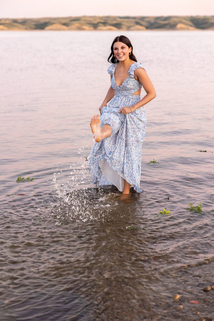 Addisyn senior beach photos wearing a light blue dress kicking water