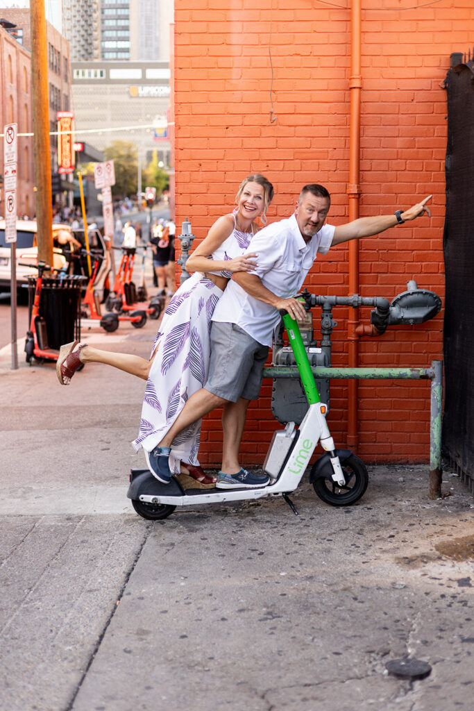 A husband and wife laugh together on an electric scooter during couples photography in Nashville 