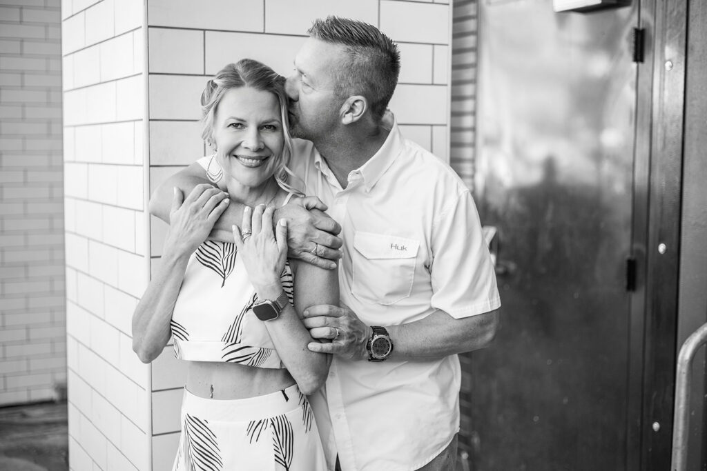 A b+w image shows a man kissing his wife's hair during couples photography in nashville