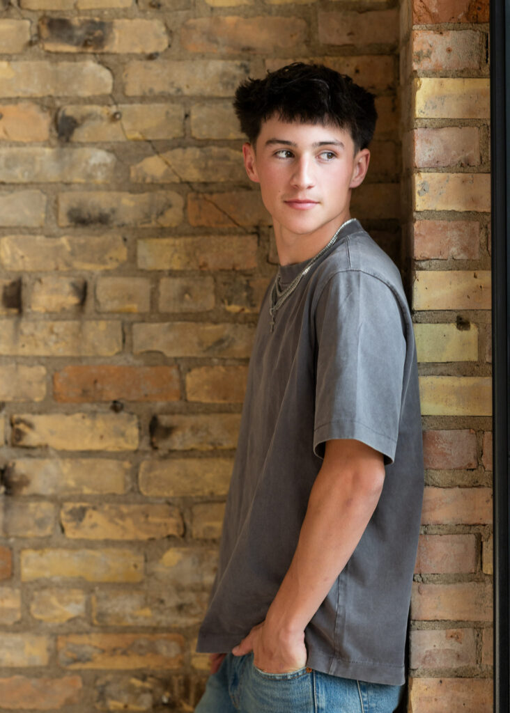 Senior Boy leaning against brick wall 