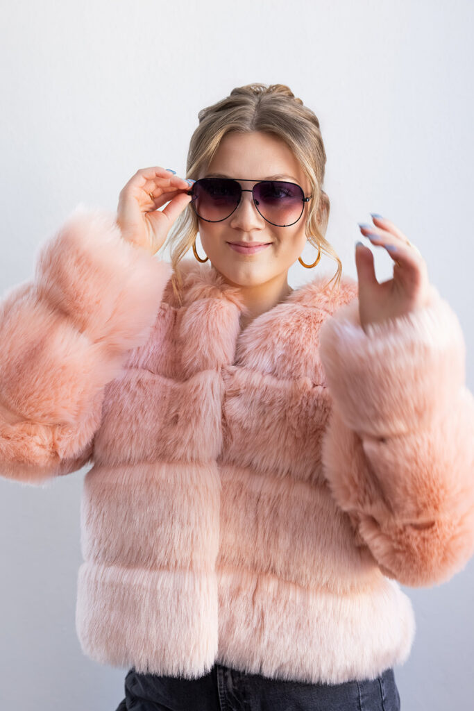 Editorial brand photo featuring fur coat and sunglasses in natural light studio