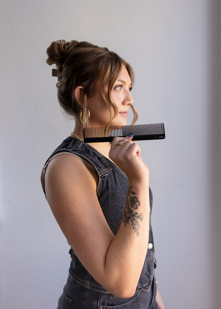 A North Dakota Cosmetology student poses with her comb during a brand photoshoot
