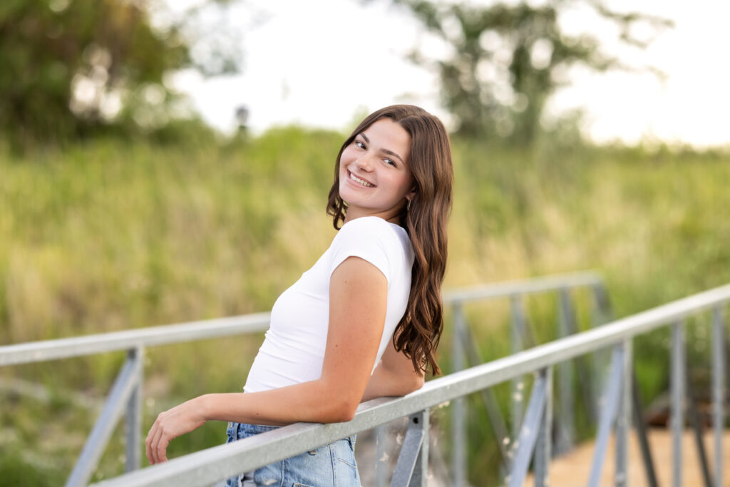 Senior Girl Leaning back on the hand rail of a bridge
