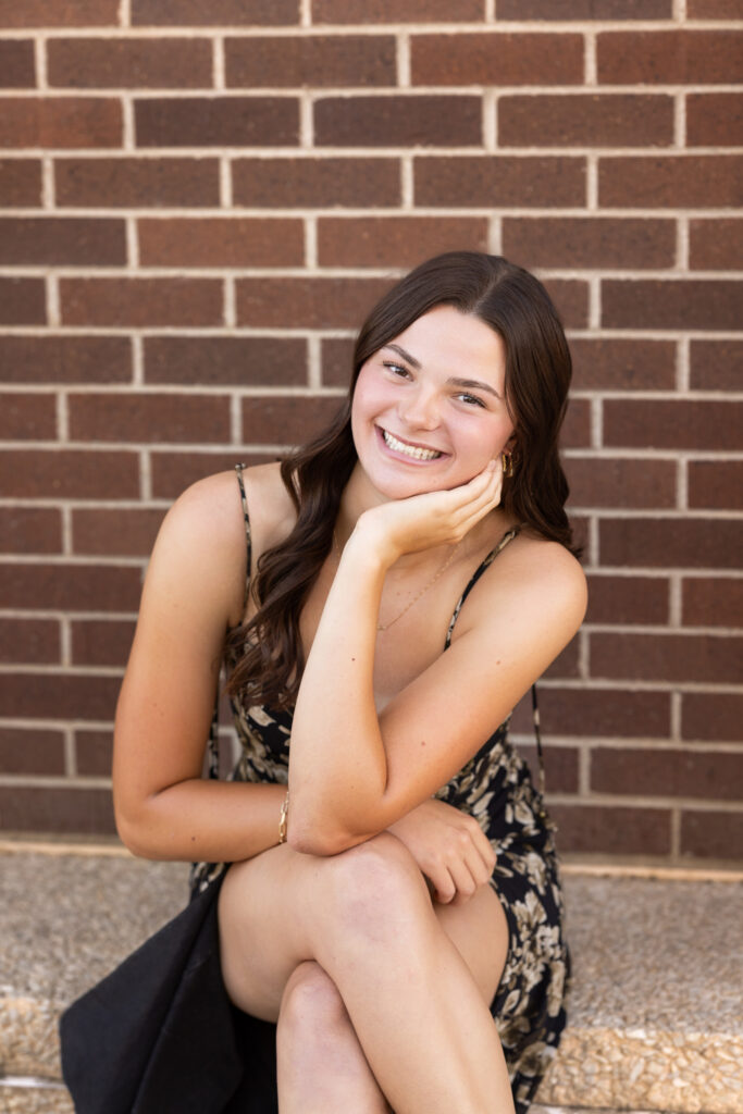 Senior Girl sitting on ledge with brick background