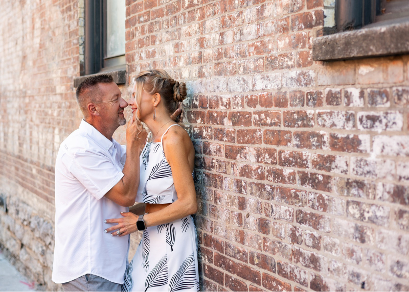 Couple sharing a quiet moment against a brick wall during a lifestyle photo session