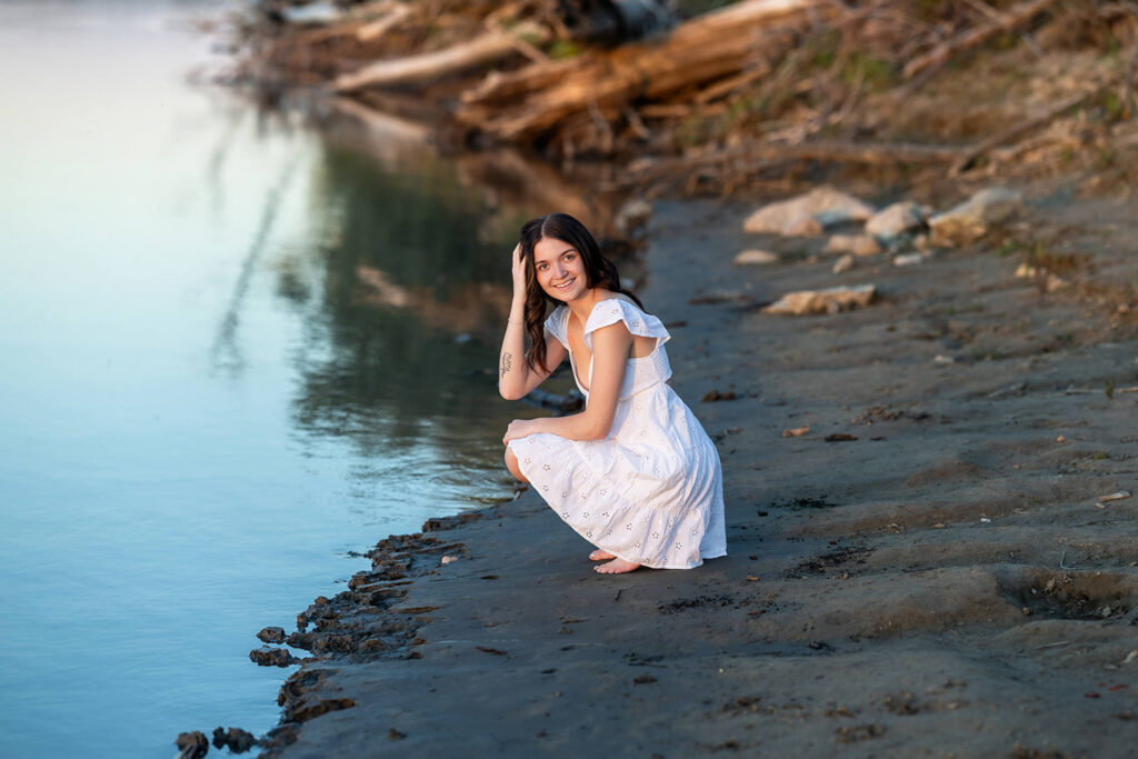 Danyn in white dress standing in water during senior session
