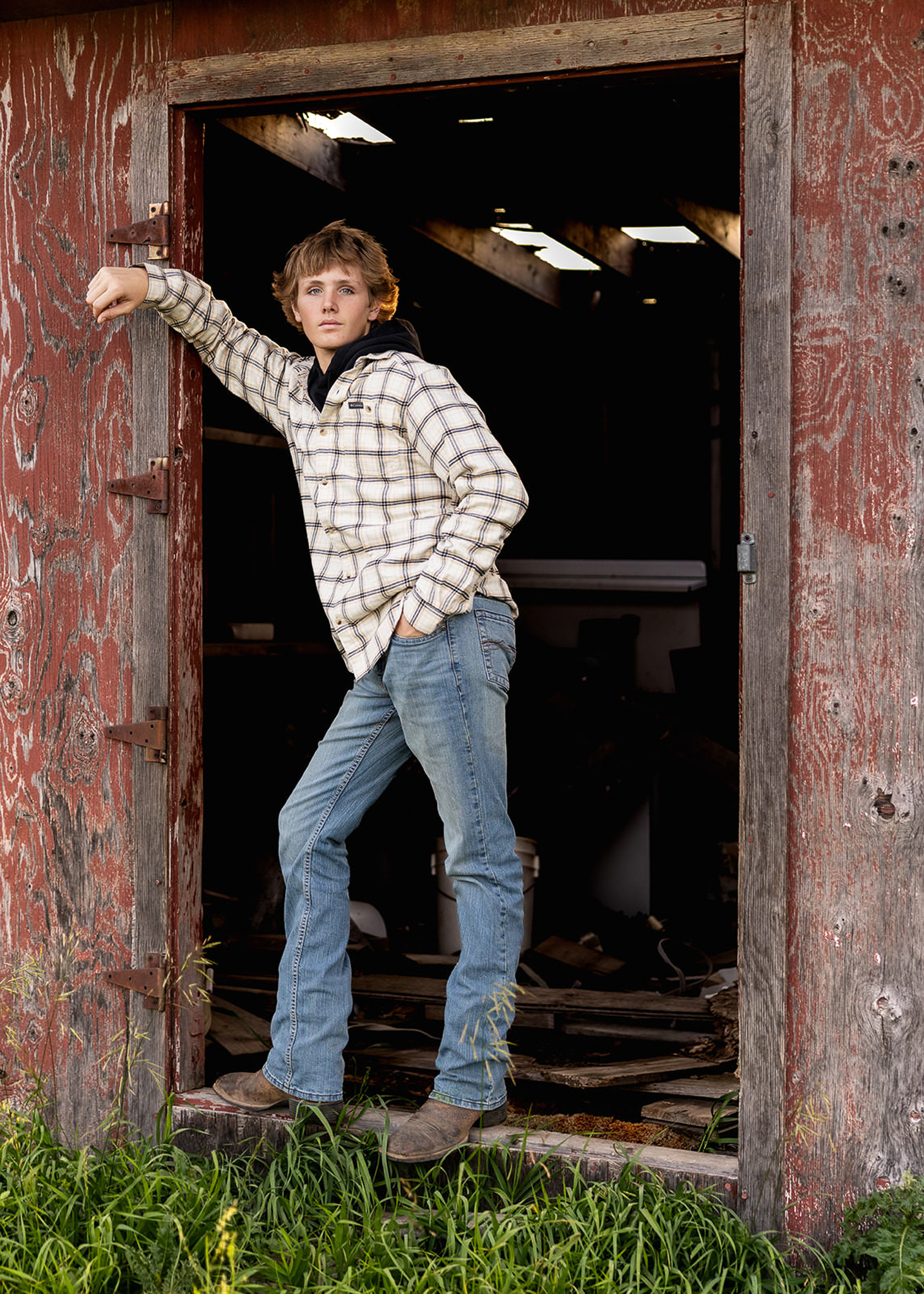 Senior boy leaning against old shed.
