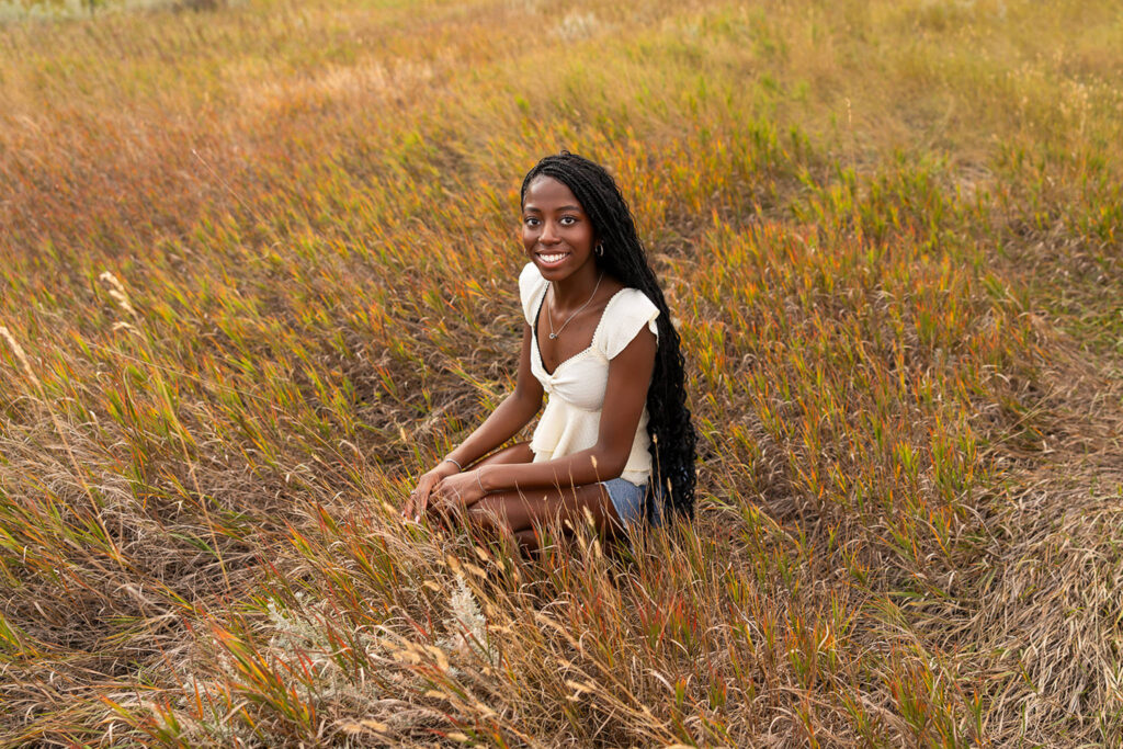Williston Senior girl squatting in a field in the fall during senior photos