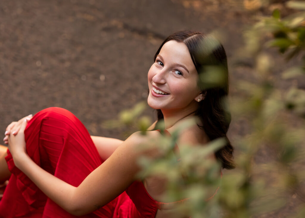 Senior girl at the Multnomah Falls in a red dress at sunset 