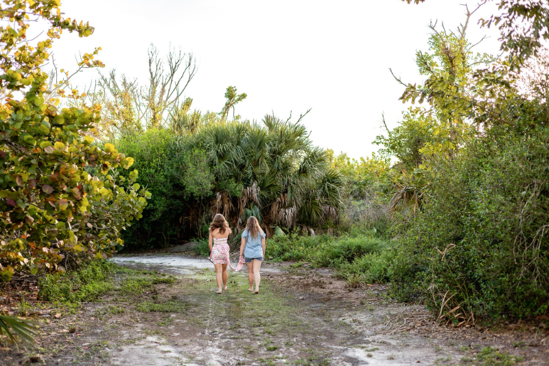 Two girls walking away on a path surrounded by greenery during a relaxed outdoor session