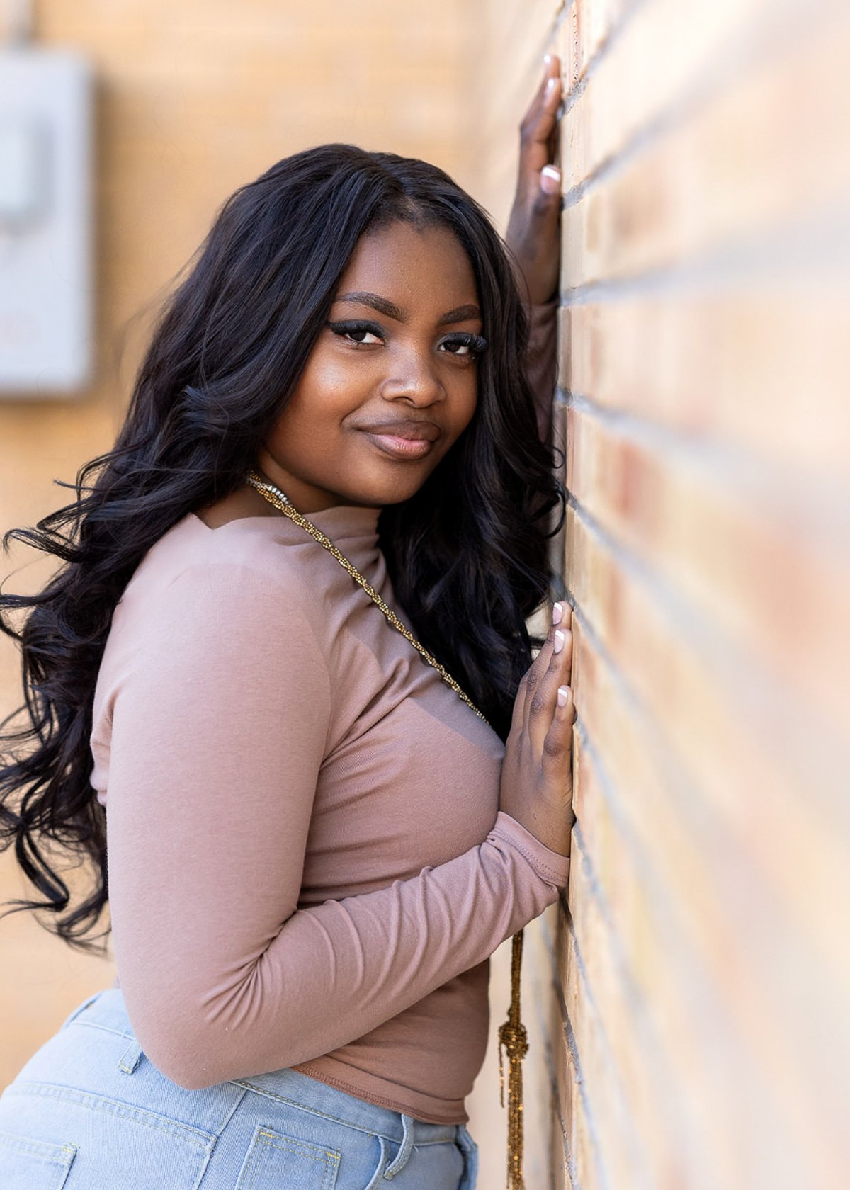 A high school senior leans against a brick wall with a confident expression, creating a portrait that feels both natural and personal. Through storytelling through photography, the image captures personality, confidence, and the excitement of this milestone season of life.