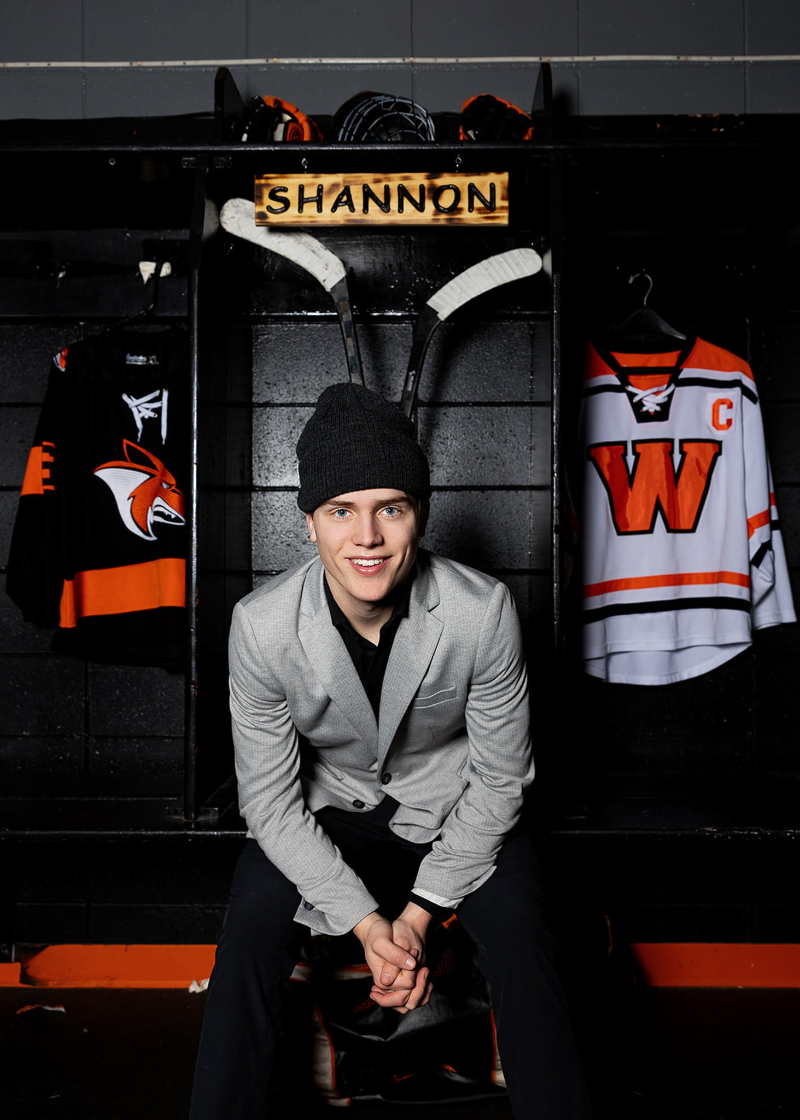 Senior posing between sports jerseys during a personalized portrait that showcases unique senior sessions and individual interests.