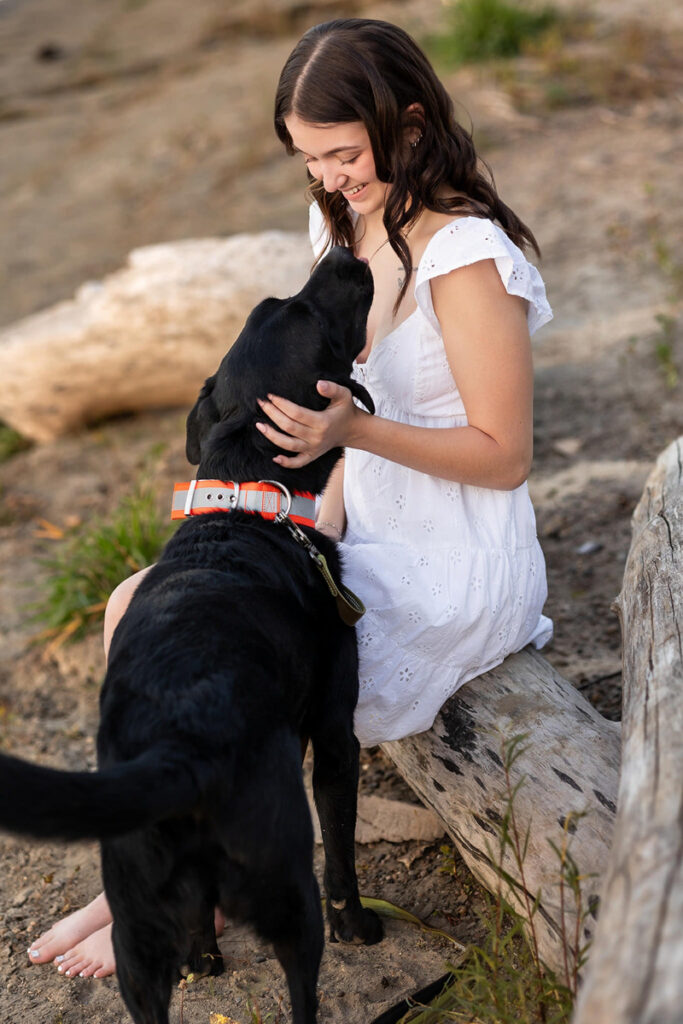Senior smiling while holding her black puppy during a personalized portrait, showcasing unique senior sessions with meaningful pets.