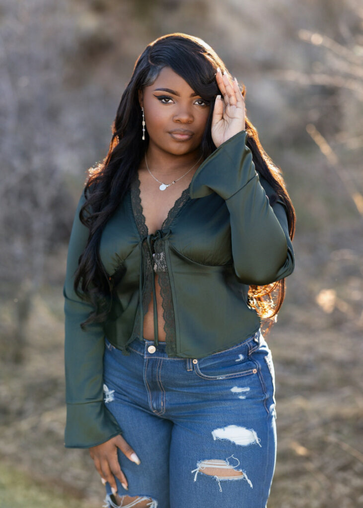Senior portrait of a graduate in a green outfit with soft natural light and a confident expression.